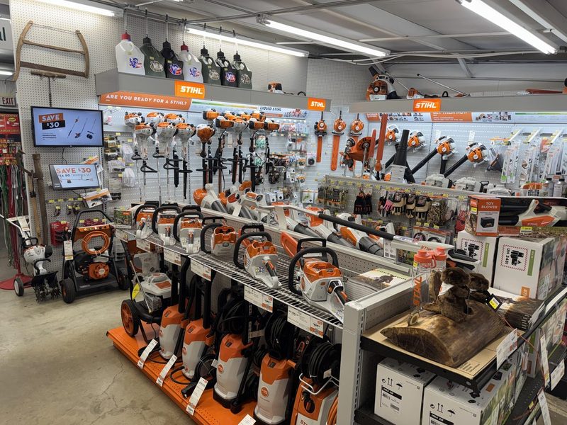 The Stihl department: chainsaws, trimmers, blowers and pressure washers on an orange-trimmed display wall and floor fixtures